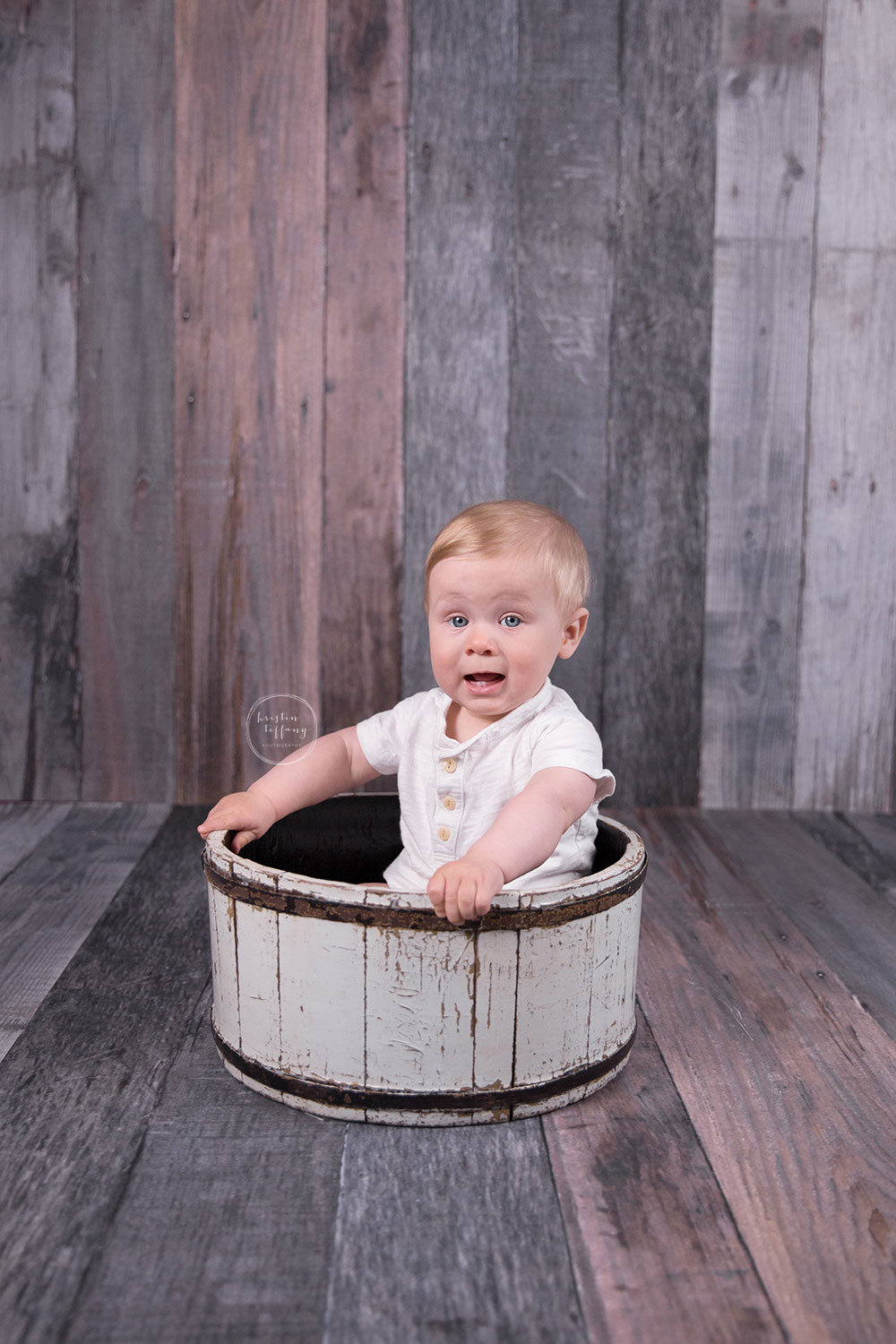 a photo of a baby boy sitting in a wooden bowl