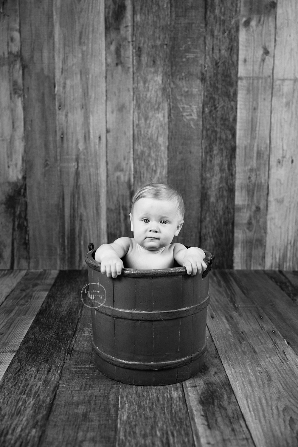 a black and white photo of a baby boy in a bucket