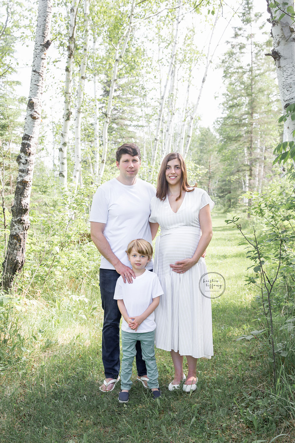 a maternity photo of a family in the forest