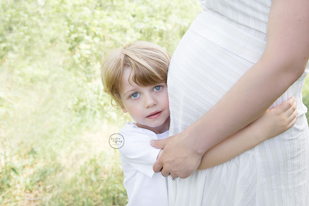 a maternity photo of a little boy hugging his mom's belly