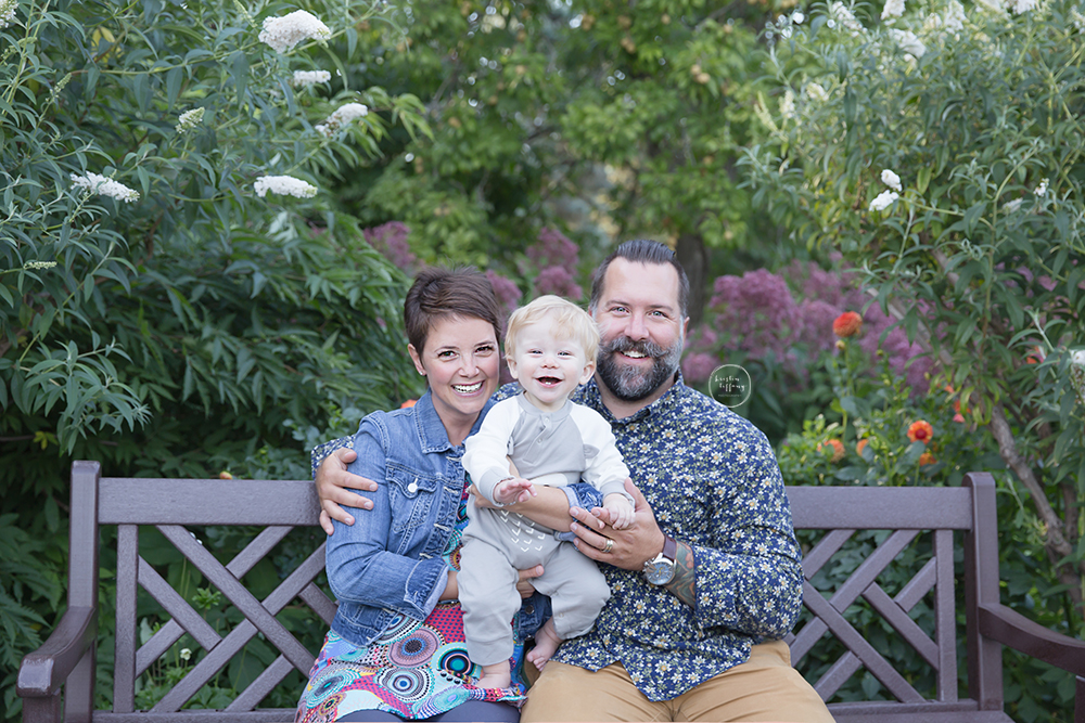 a photo of a family on a park bench surrounded by flowers
