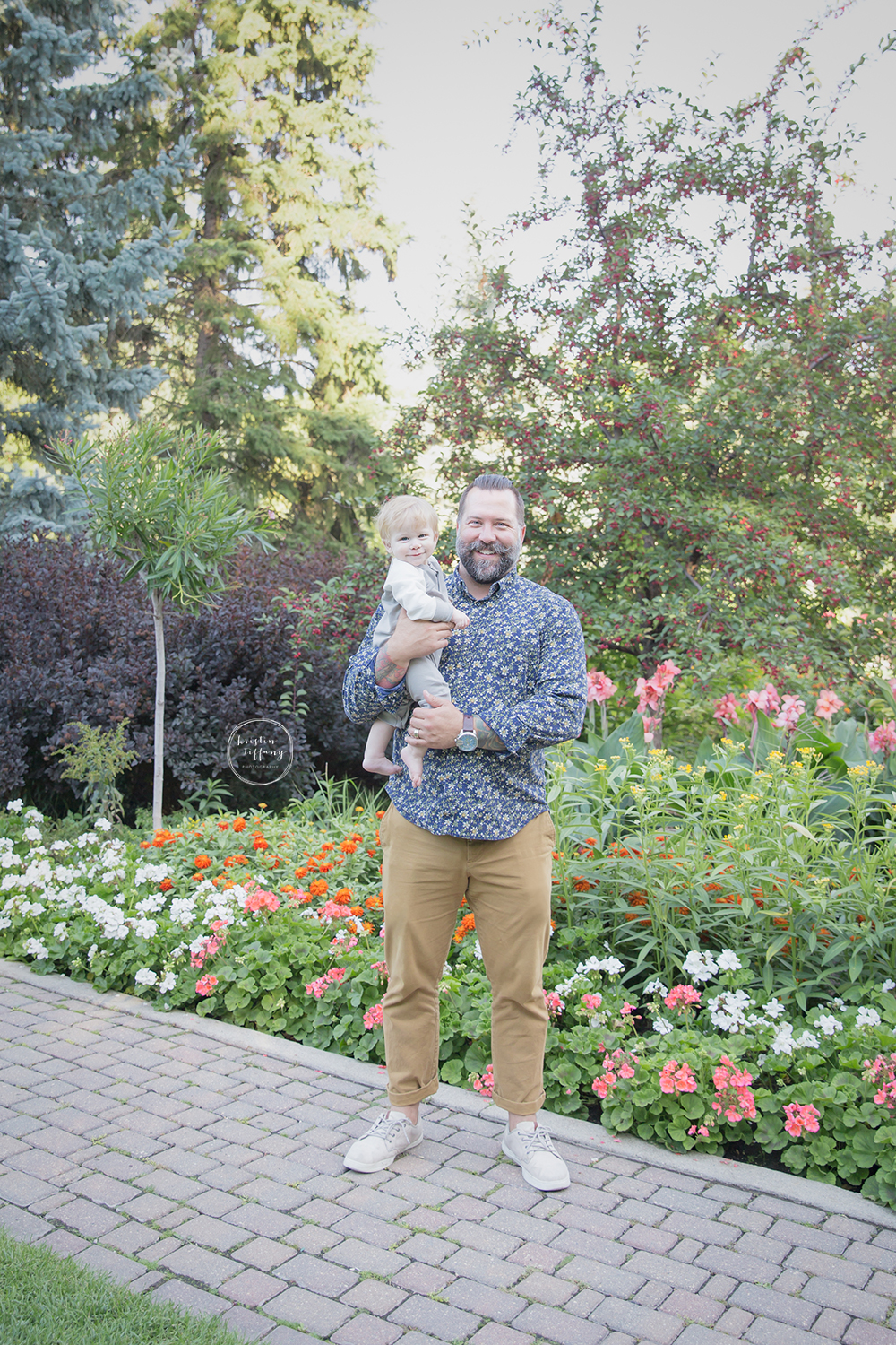 a photo of a father holding his son by a flower garden