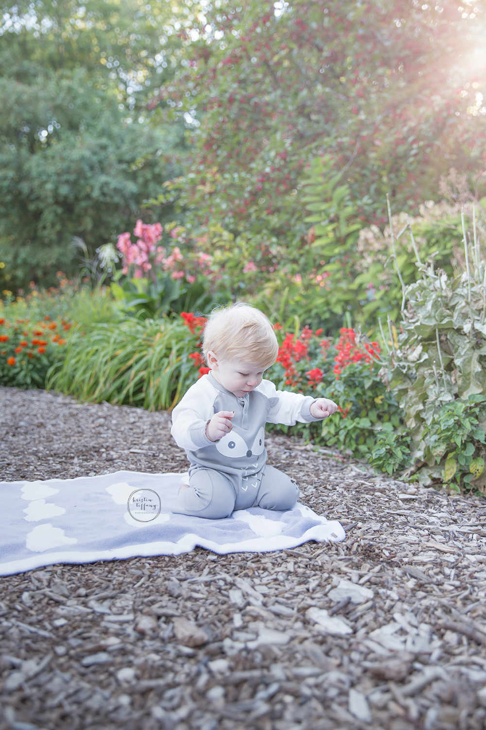 a photo of a baby boy playing by some flowers