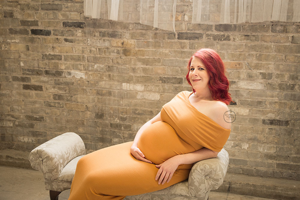 a maternity photo of a woman in a mustard yellow dress