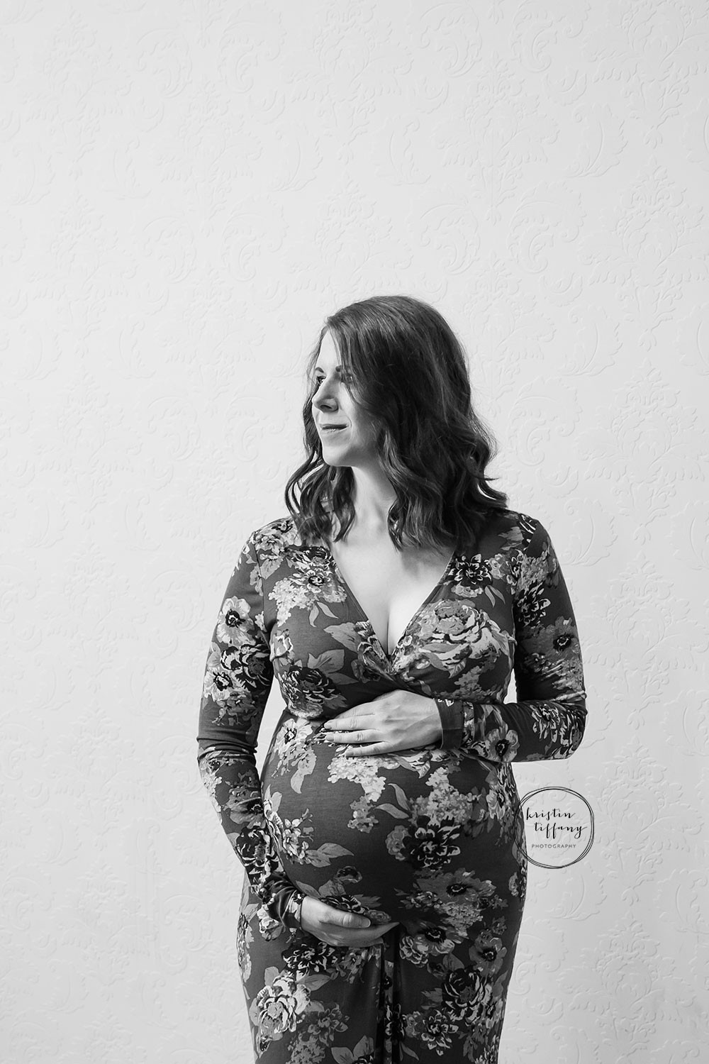 a black and white photo of a pregnant woman in a floral dress