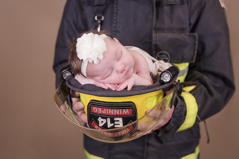 a photo of a baby girl sleeping in her dad's firefighter helmet