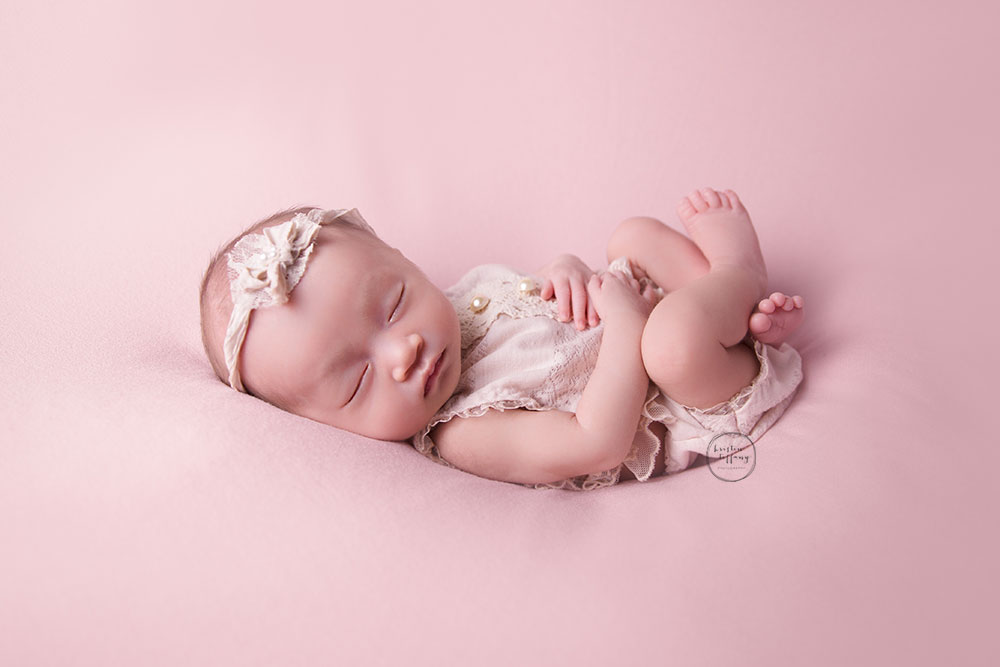 a photo of a newborn baby girl sleeping in an outfit