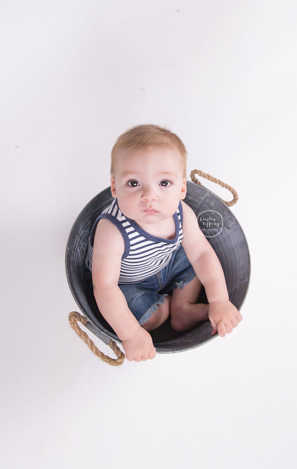 a photo of a baby boy sitting in a metal bucket