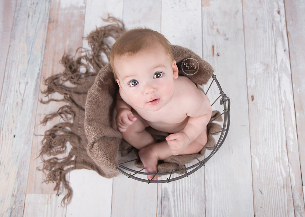 a photo of a baby boy sitting in a wire basket