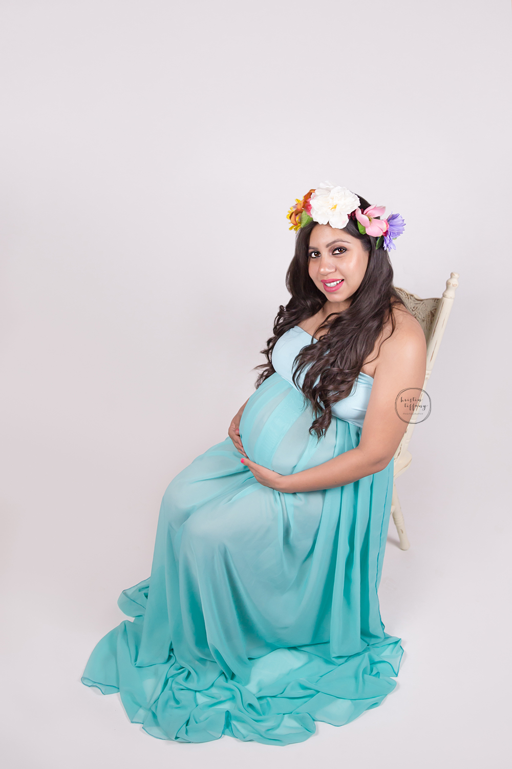 a maternity photo of a mother wearing a gown and floral crown