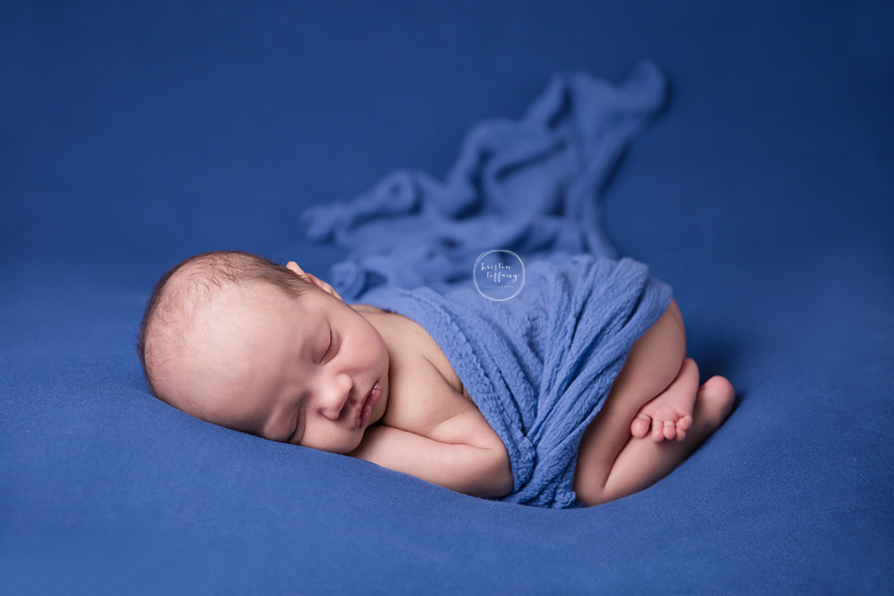 a posed newborn photo of a boy in blue