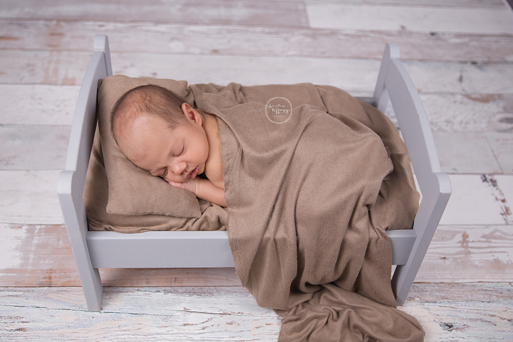 a photo of a newborn sleeping in a doll bed
