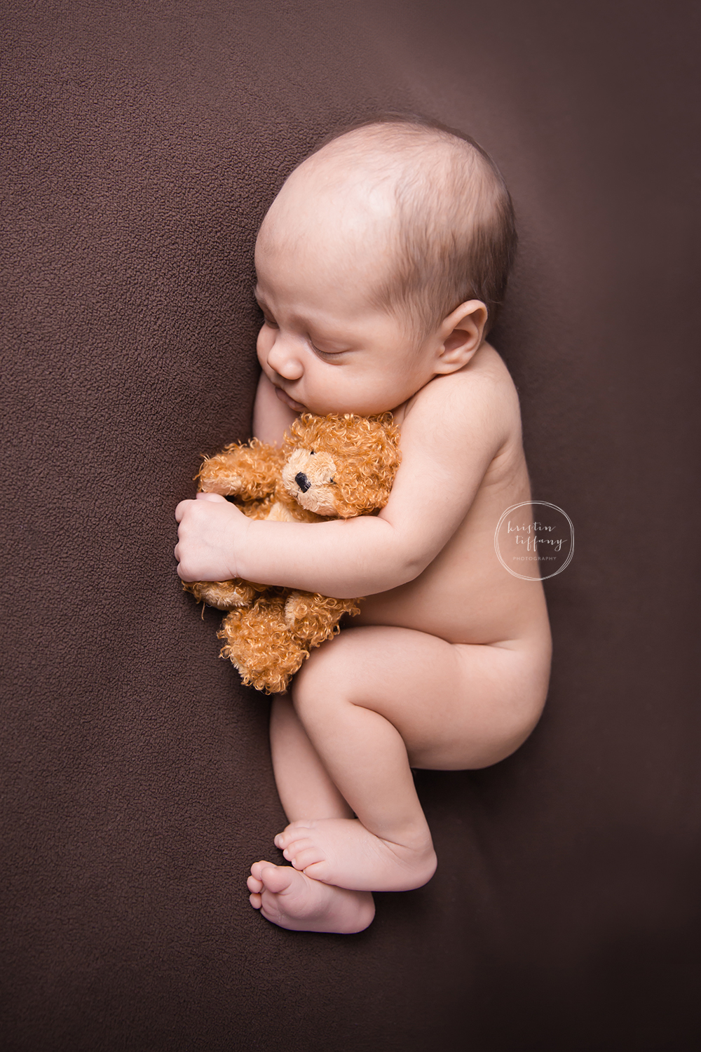 a photo of a newborn baby with a small teddy bear