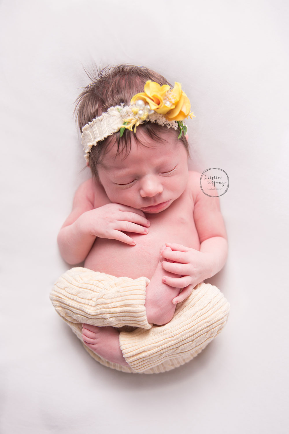 a photo of a posed newborn baby girl with a yellow outfit