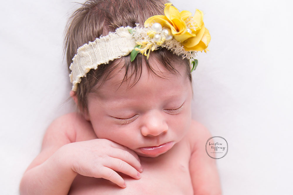 a photo of a newborn sleeping in a yellow headband