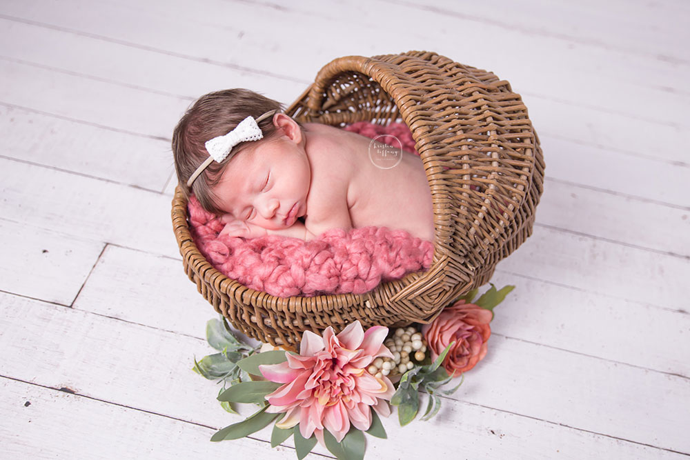 a photo of a newborn baby girl asleep in a small basket