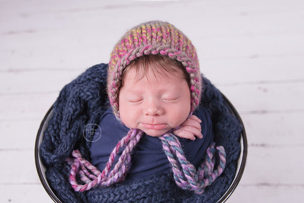 a photo of a newborn baby smiling in a bucket