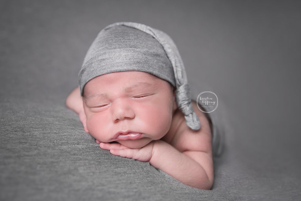 a photo of a newborn baby boy in a grey sleepy cap