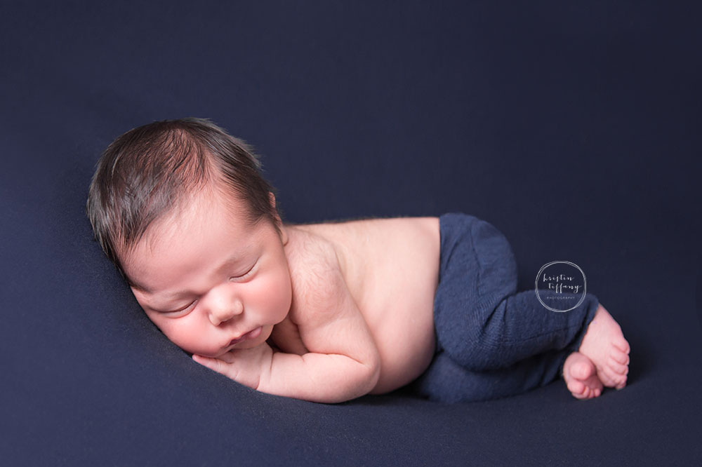 a photo of a newborn boy sleeping on a blue backdrop and blue pants