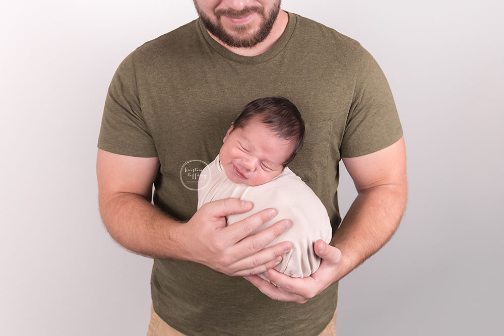 a photo of a new dad holding his smiling newborn son