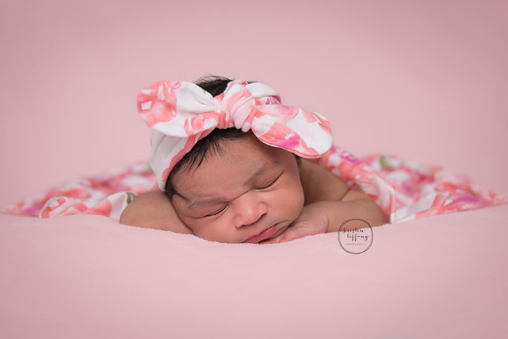 a newborn photo of a baby girl with a floral headband and wrap