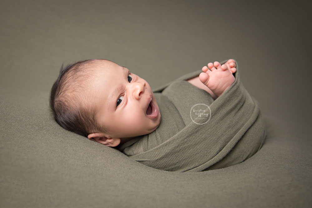 a photo of a baby boy swaddled in a green wrap