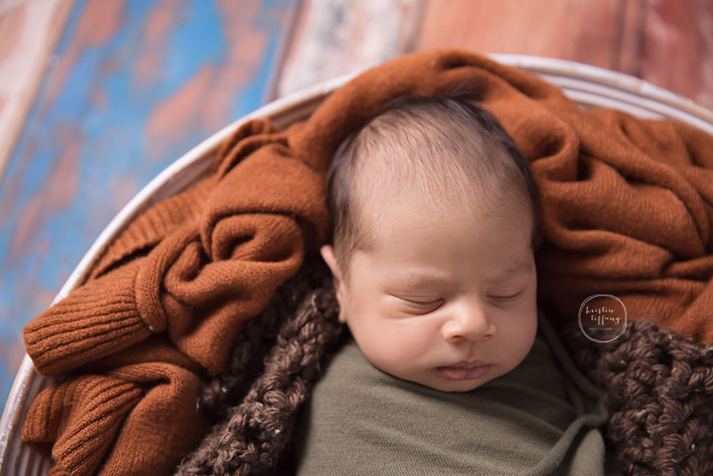 a photo of a baby boy sleeping in an orange blanket