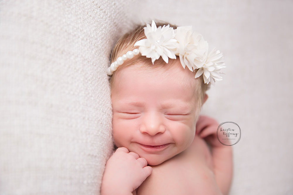a photo of a smiling newborn baby girl in a pretty headband