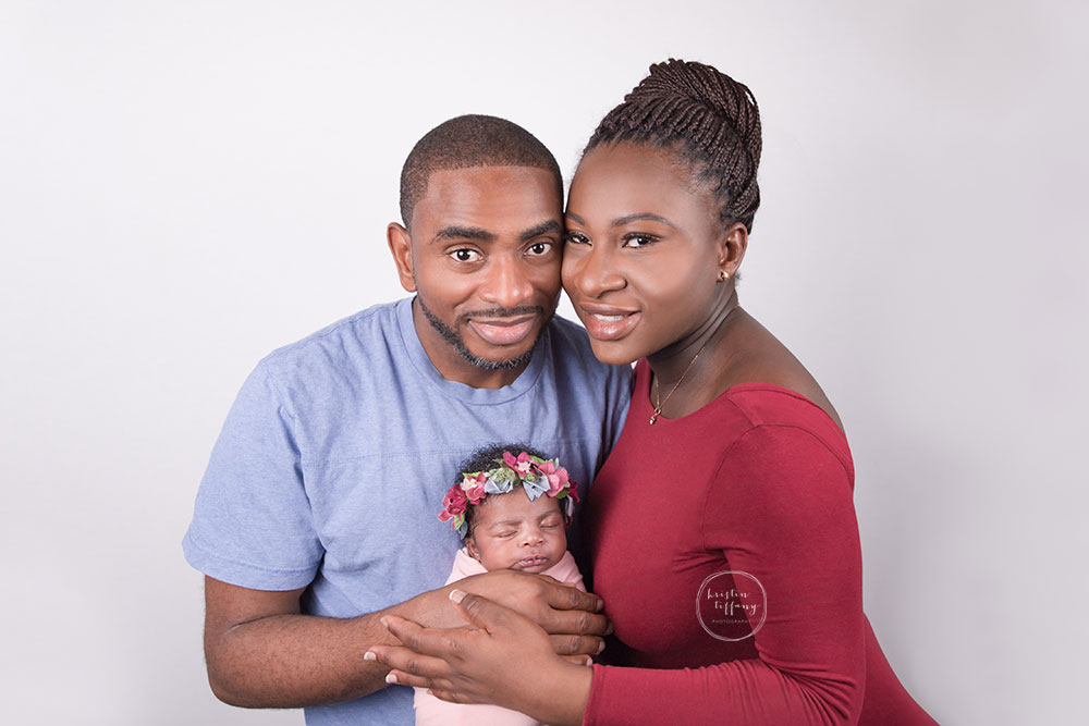 a photo of a newborn baby girl with her parents at a posed newborn session
