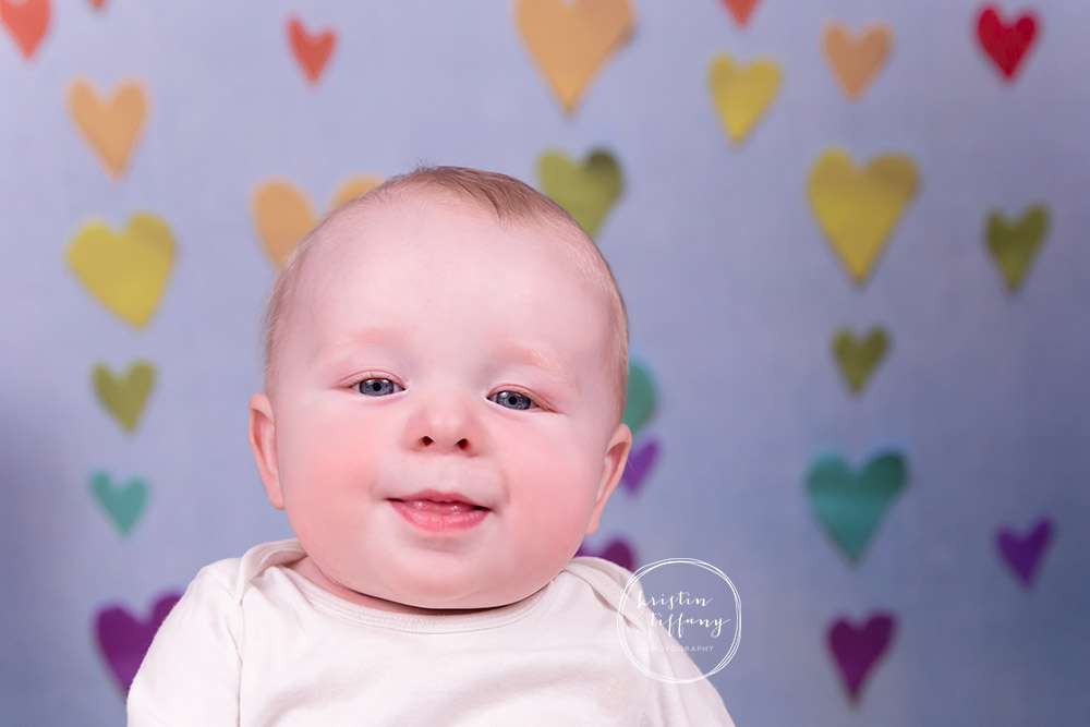 a photo of a baby boy with a valentine heart backdrop