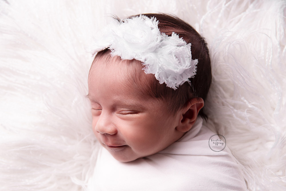 a newborn photo of a baby girl smiling