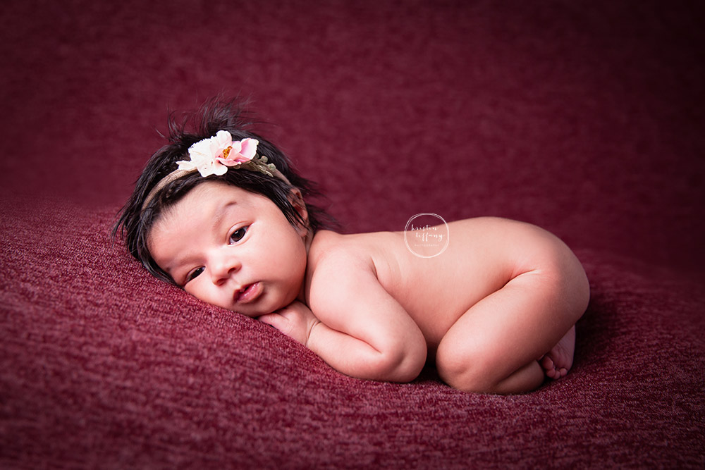 a photo of a newborn baby girl posed on a beanbag