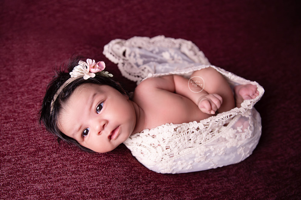 a photo of a baby girl wrapped in a lace scarf