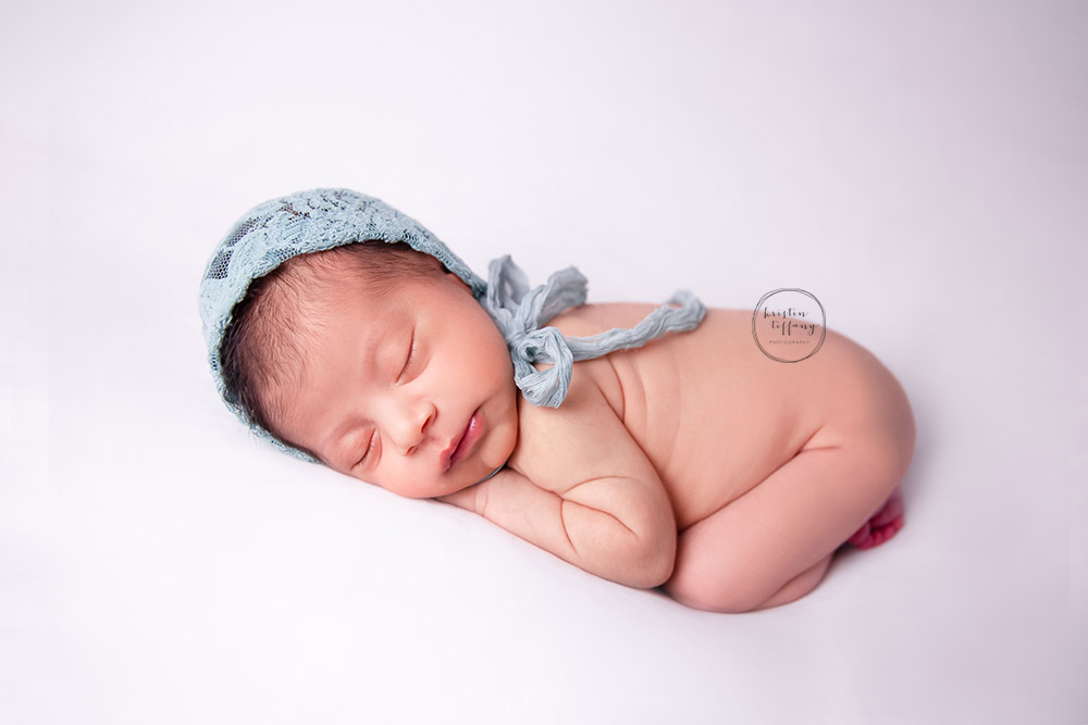 a newborn photo of a baby girl sleeping in a lace bonnet