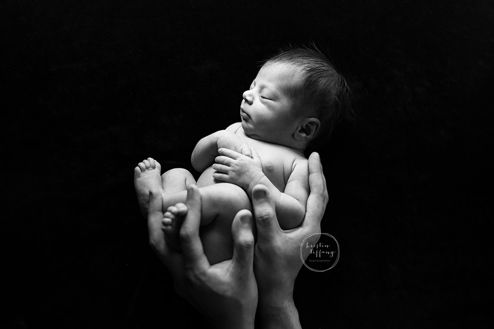 a newborn photo of a baby in her daddy's hands
