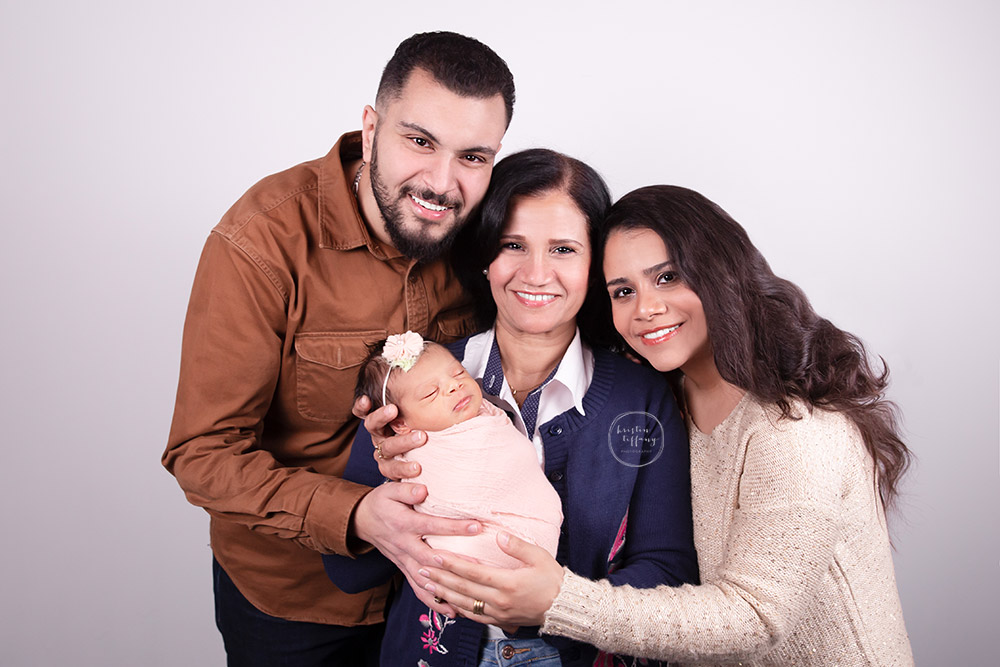 a newborn photo of a baby girl with her parents and grandmother