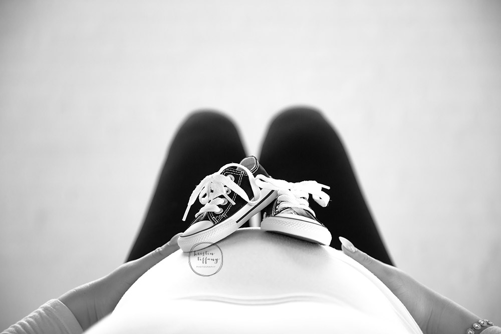 a maternity photo of a women with baby shoes on her belly