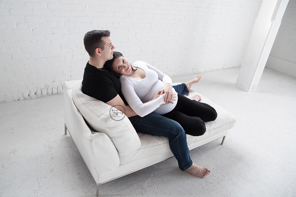 a maternity photo of a couple laying on a sofa
