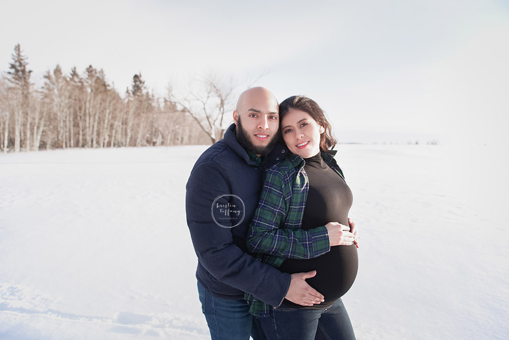 a maternity photo of a couple in the snow
