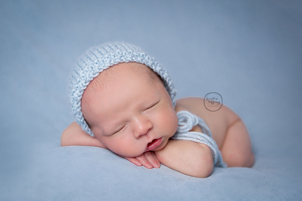 a posed newborn session of a baby boy in a blue bonnet