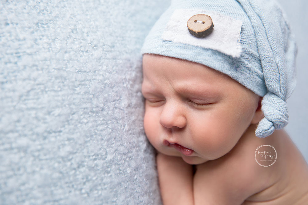 a posed newborn session of a baby boy in a sleepy cap