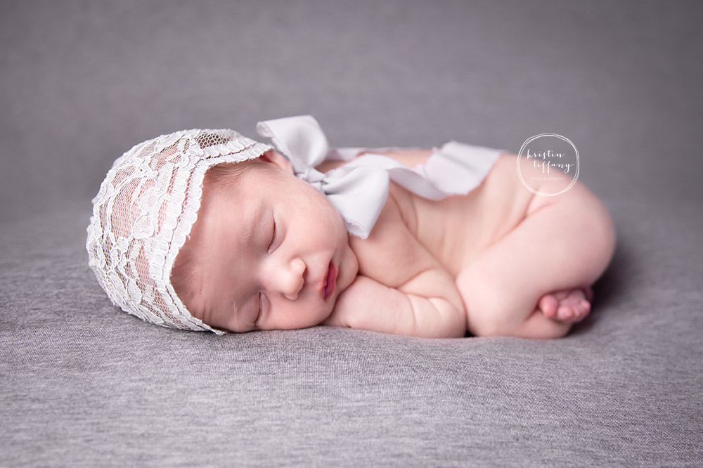 a newborn photo of a baby girl posed in a lace bonnet