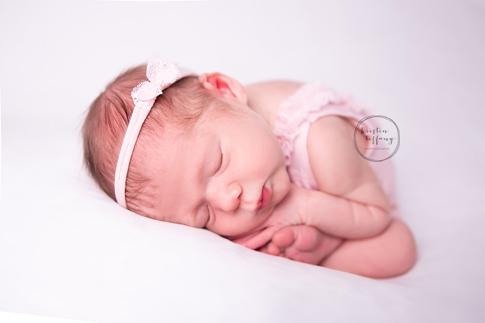 a newborn photo of a baby girl in taco pose