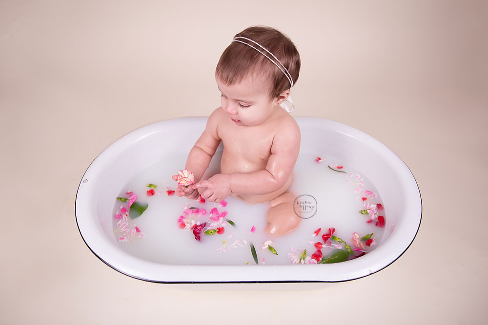 a photo of a baby girl having a post cake smash floral bath