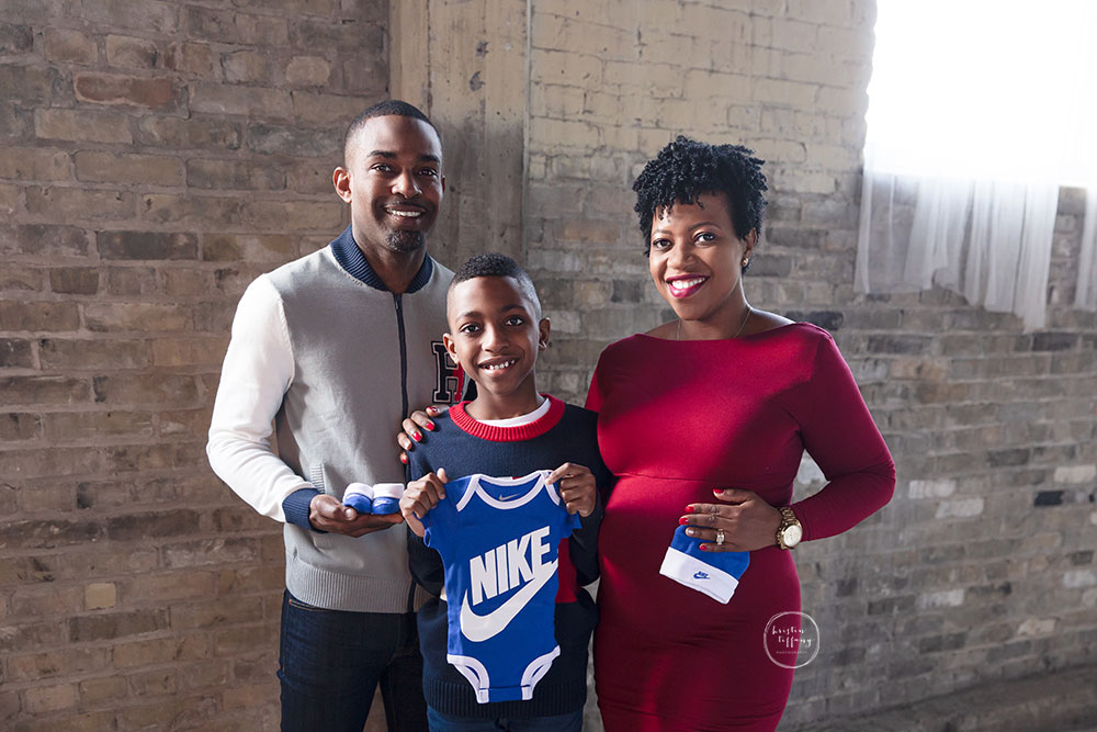 a maternity photo of a family holding blue clothing and accessories