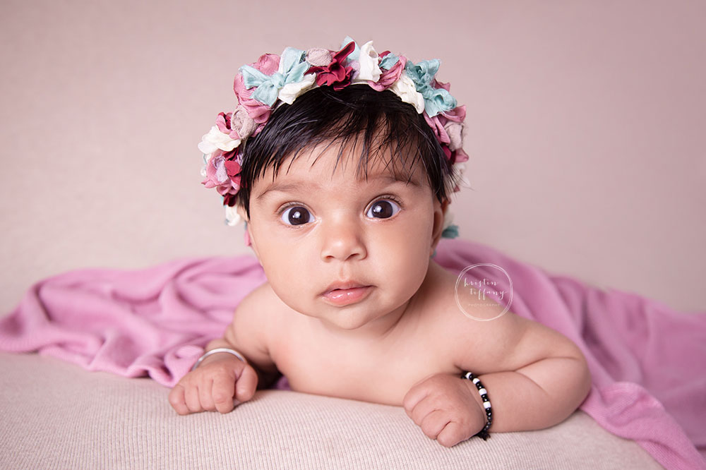 a photo of a baby girl on her tummy at a baby photo session