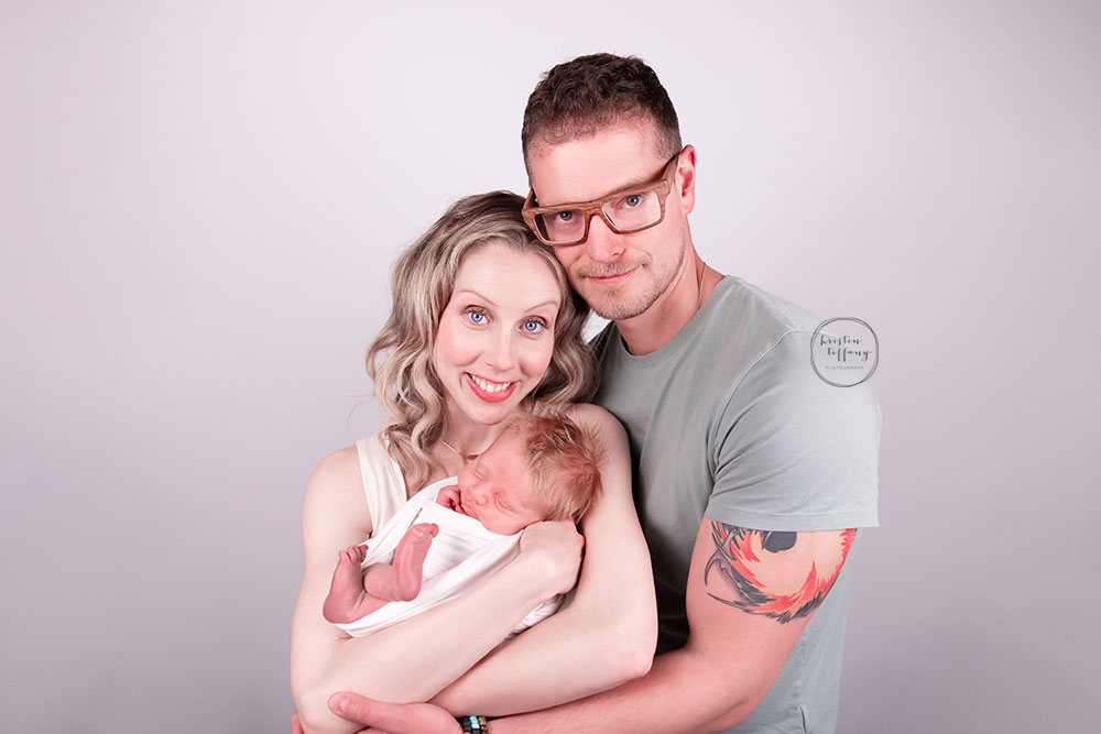 a photo of baby boy and his parents at his newborn photo session