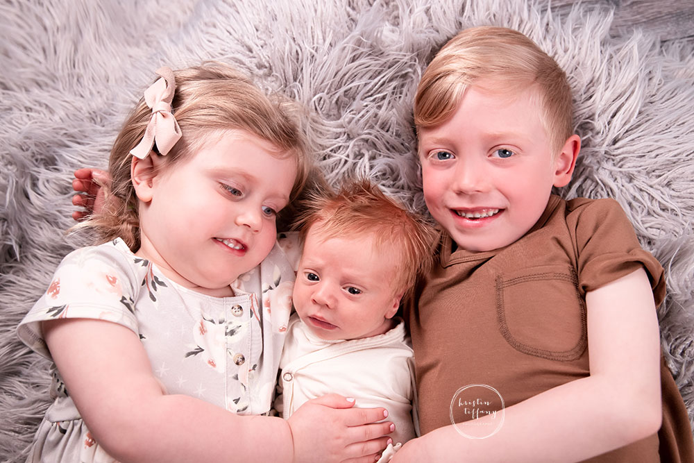 a photo of baby boy and his siblings at his newborn photo session
