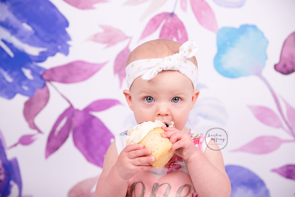 a photo of a baby girl eating a cupcake at a photoshoot