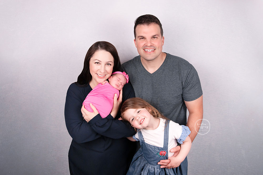 a photo of a baby girl and her family at her newborn photoshoot